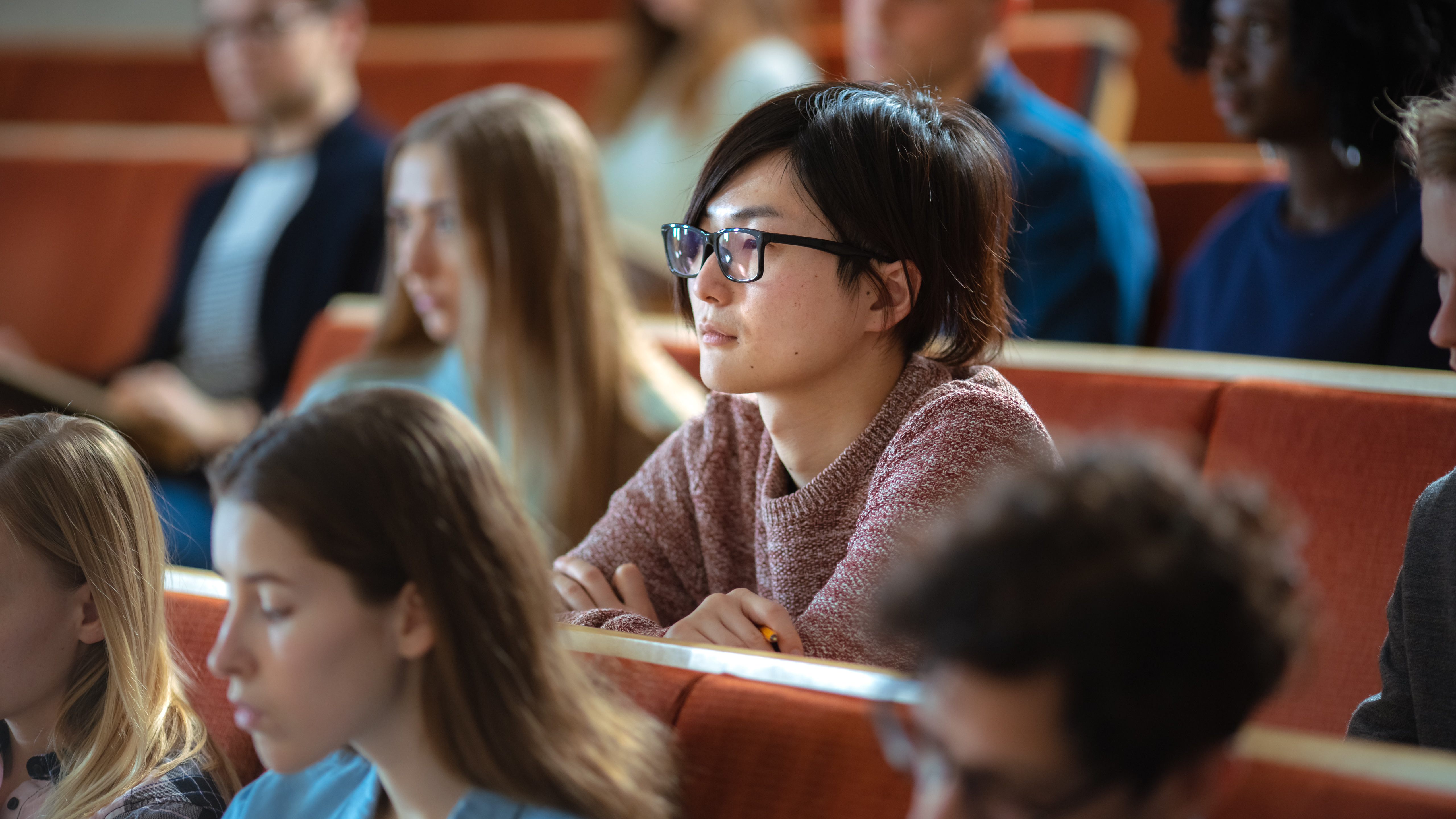 Asian Young Man Among His Fellow Students in the Classroom. Young Bright People Listening to a Lecture and Take Notes while Studying at the University. Student listening to lecture